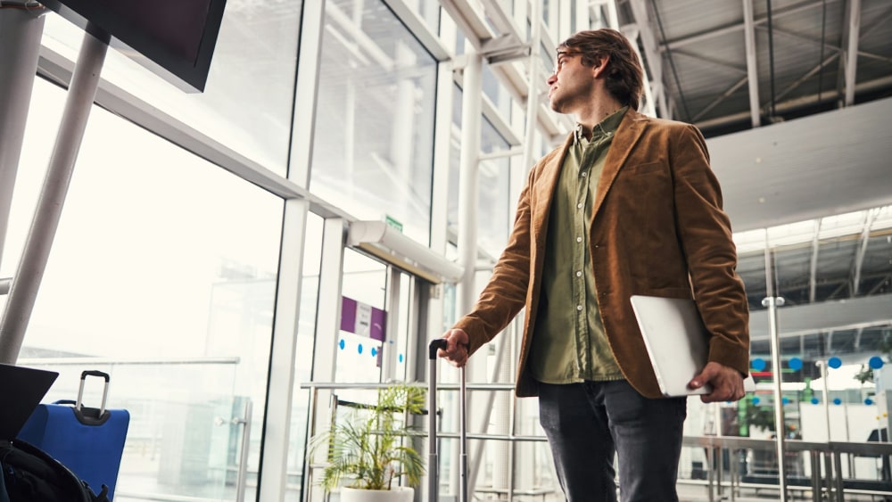 Travel airport scene, businessman holding laptop in airport lounge